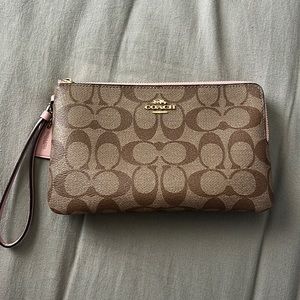 Large Coach wristlet wallet in the shade khaki with pink detailing.